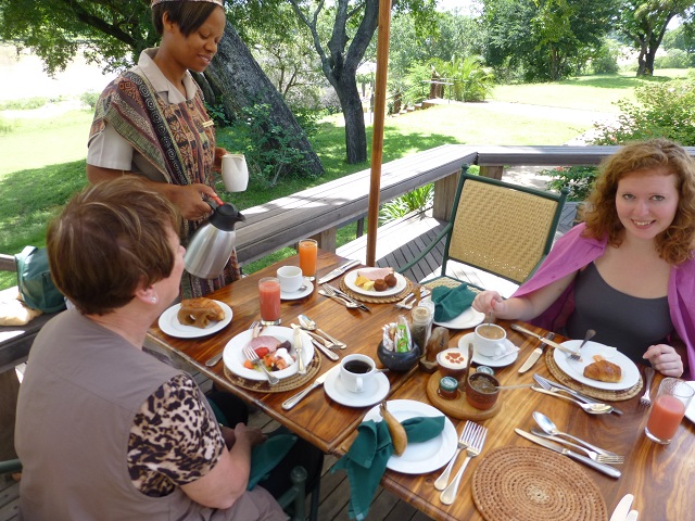 Every meal was scrumptuous.  Here, we're able to eat breakfast on a deck that overlooks the Sand River (Marnie at left, Brianna at right).  We saw a couple of animals stroll across the adjacent lawn.  Photo by FG.